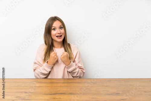 Teenager girl in a table celebrating a victory