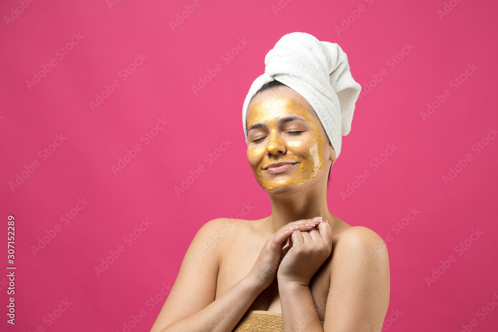 Beauty portrait of woman in white towel on head with gold nourishing mask on face. Skincare cleansing eco organic cosmetic spa relax concept. Beauty portrait of woman in white towel on head with gold nourishing mask on face. Skincare cleansing eco organic cosmetic spa relax concept.