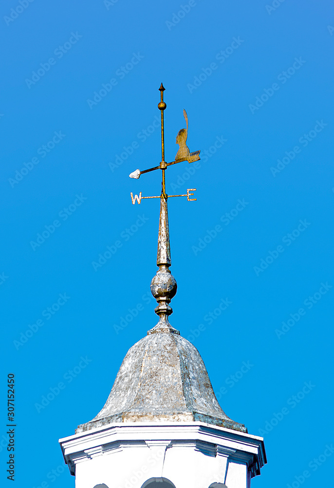 A WEATHER VANE made as an Indian Head silhouette with directional points attached to a post on top of a tower of a building A WEATHER VANE made as an Indian Head silhouette with directional points attached to a post on top of a tower of a building