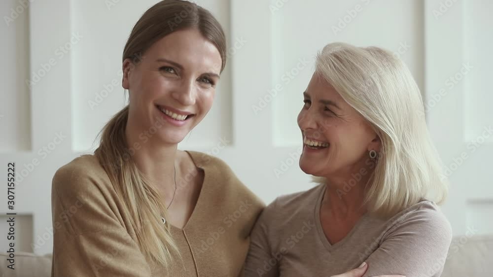 Smiling grown up daughter embracing happy middle aged mommy. Smiling grown up daughter embracing happy middle aged mommy.
