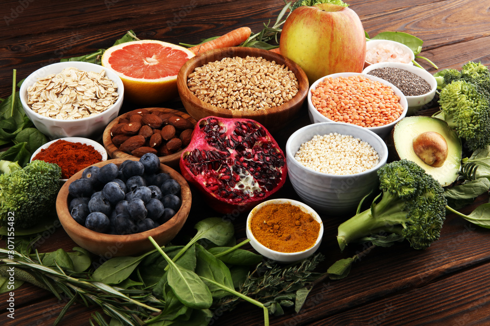 Healthy food clean eating selection: fruit, vegetable, seeds, superfood, cereals, leaf vegetable on rustic background