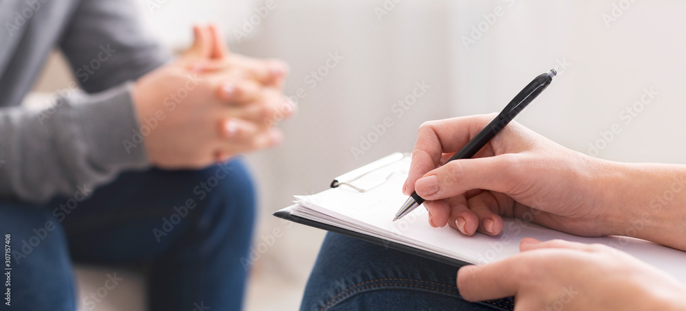 Therapist writing notes during rehab session with patient - obrazy, fototapety, plakaty 