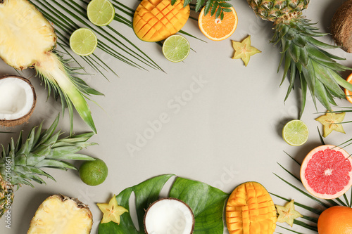 Fototapeta Naklejka Na Ścianę i Meble -  Composition with exotic fruits and palm leaves on grey background, space for text