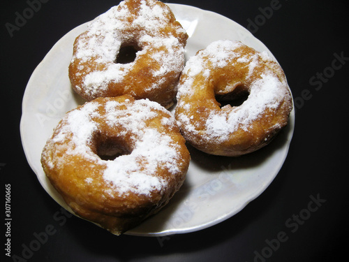 Donuts on a white saucer and a black background.