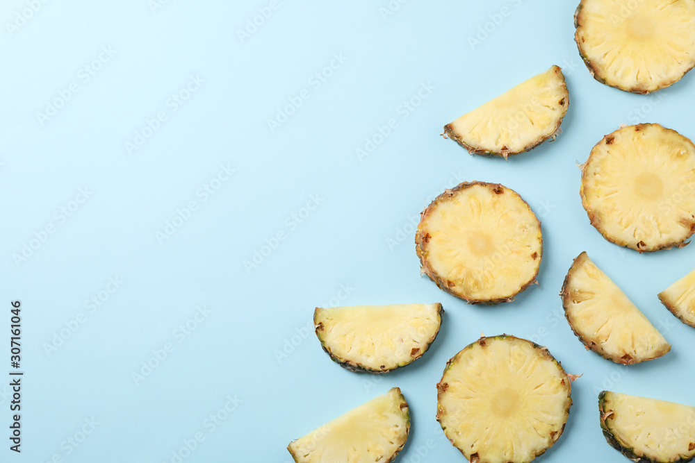 Flat lay with pineapple slices on blue background, space for text