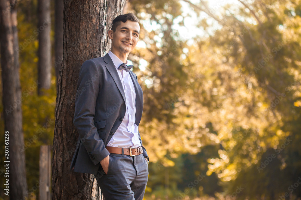 Happy handsome young businessman standing in the park Happy handsome young businessman standing in the park