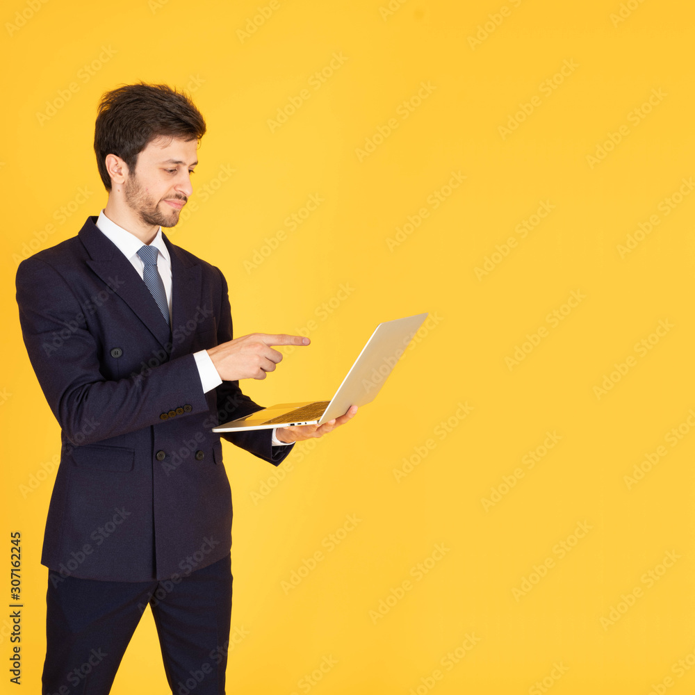 man in suit with a tie Handsome looking face with beard In the businessman look Holding and pointing at a notebook to work or communicate business. There is space on the right in the yellow background