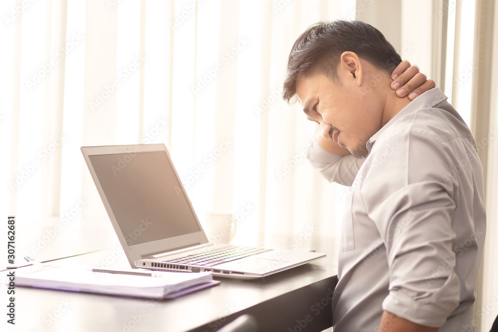 Asian office workers are suffering from neck pain from sitting on a laptop for a long time.Asian men are aching from hard work. Asian office workers are suffering from neck pain from sitting on a laptop for a long time.Asian men are aching from hard work.