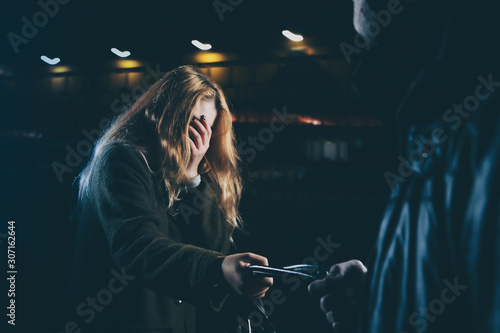 Fotografia GIRL SELF DEFENSE A young woman sees a suspicious person walking behind her and plans to defend herself against a male attacker in an alley