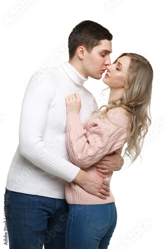 Loving guy and girl are standing in an embrace in casual clothes and kissing Isolated on a white background.