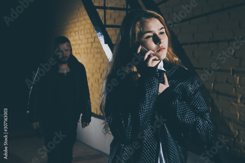 Foto Shot of a scared young woman looking at a man who's holding a knife behind his b