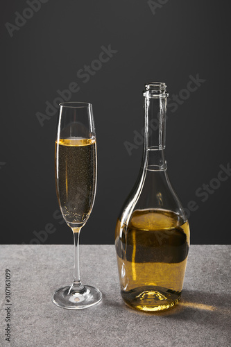 glass and bottle of sparkling wine for celebrating christmas eve on grey