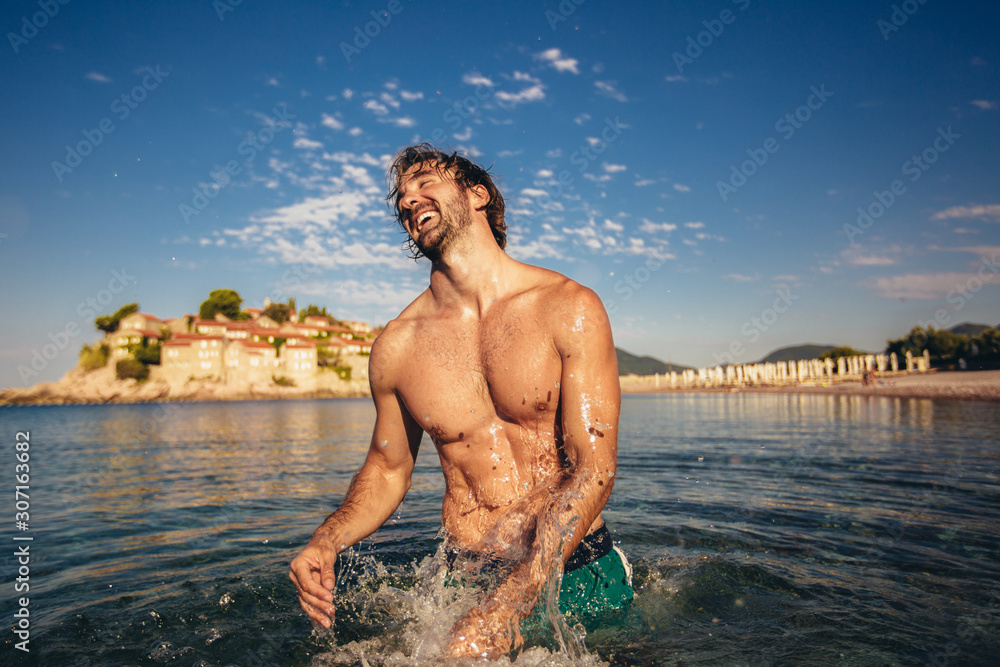 Fototapeta premium Handsome young man posing on the beach by the sea