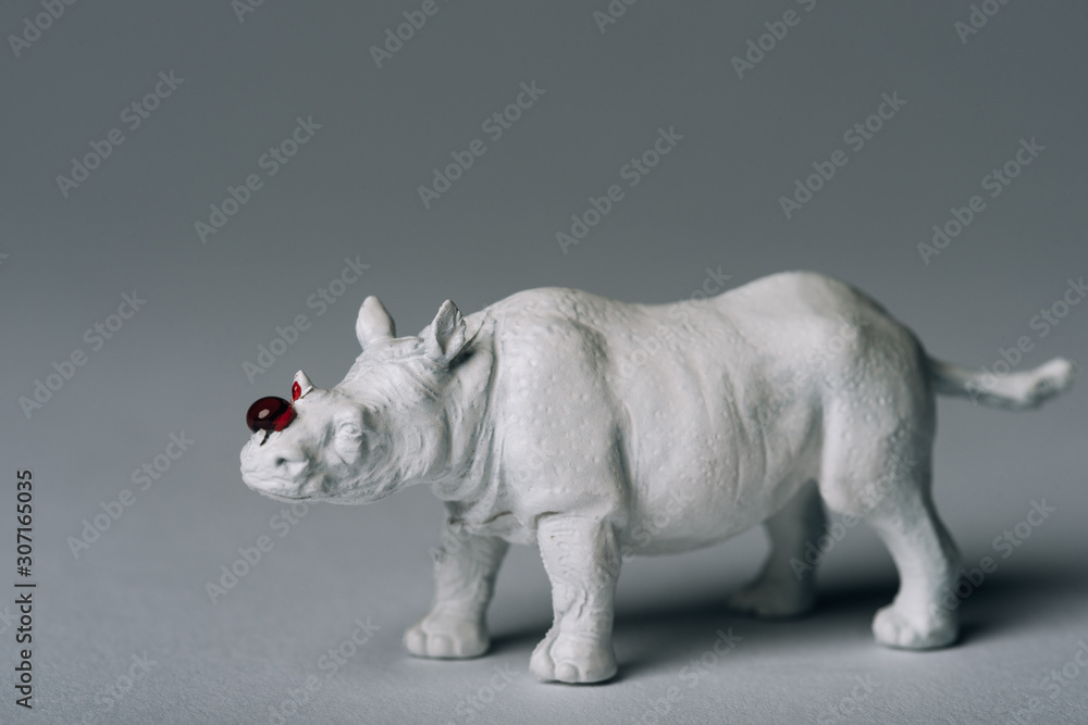 White toy rhinoceros with blood on grey background, hunting for horn concept White toy rhinoceros with blood on grey background, hunting for horn concept