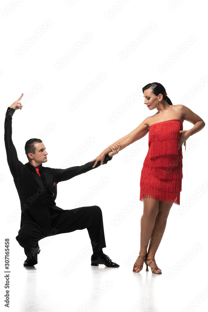 elegant dancer squatting and holding hand of attractive partner while performing tango on white background elegant dancer squatting and holding hand of attractive partner while performing tango on white background