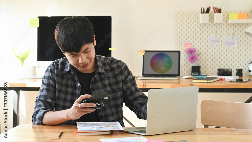 Young graphic designer working his camera and laptop in creative studio. Young graphic designer working his camera and laptop in creative studio.