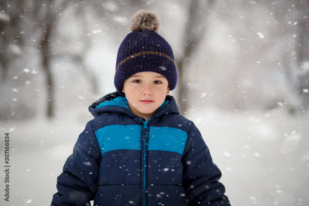 Adorable, cute boy playing with snow cheerfully. Wintertime, kids activity