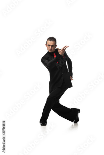 handsome, stylish dancer looking at camera while performing tango on white background