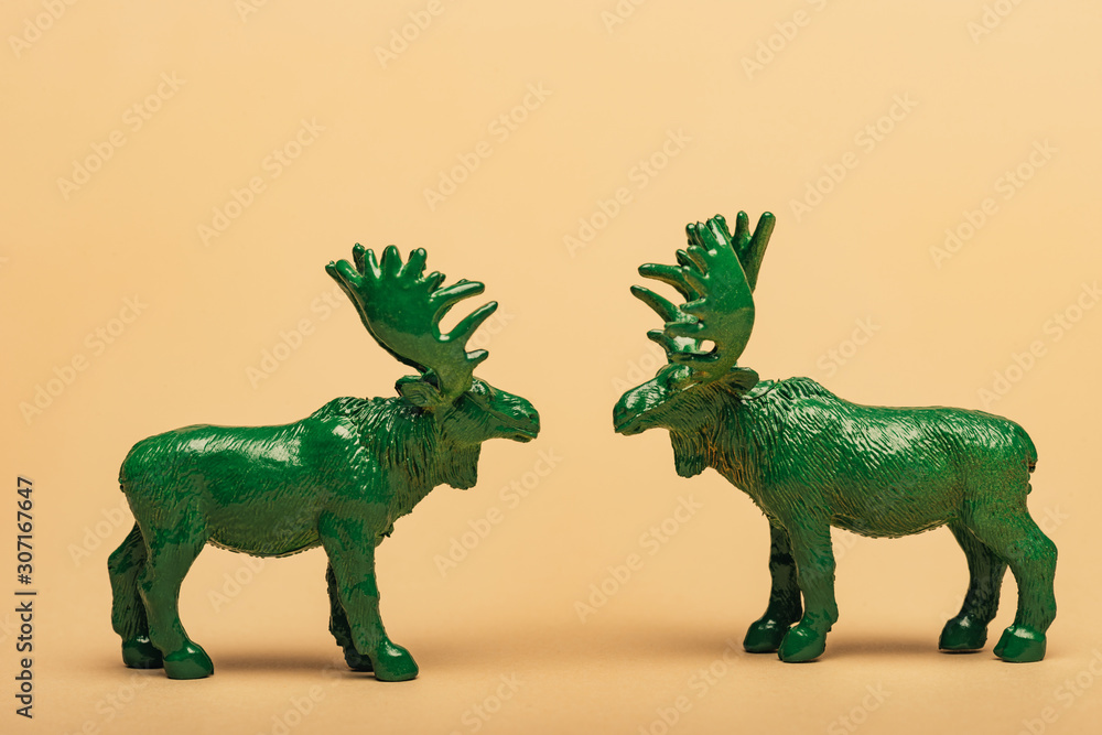 Obraz premium Green toy moose on yellow background, hunting for horns concept