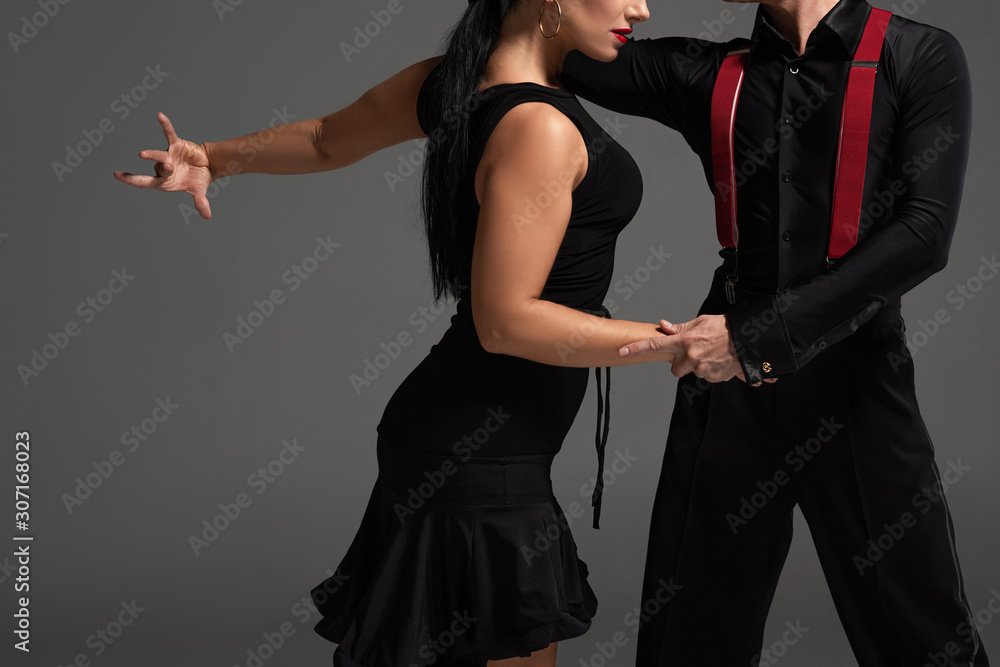 cropped view of elegant dancers in black clothing performing tango isolated on grey