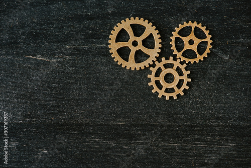 top view of vintage metal gears on dark wooden background with copy space © LIGHTFIELD STUDIOS