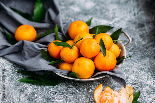  Ripe tangerines in a plate on a gray table