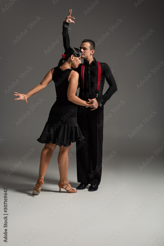two expressive dancers in black clothing performing tango on grey background two expressive dancers in black clothing performing tango on grey background
