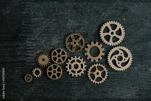 top view of retro metal gears on dark wooden background © LIGHTFIELD STUDIOS