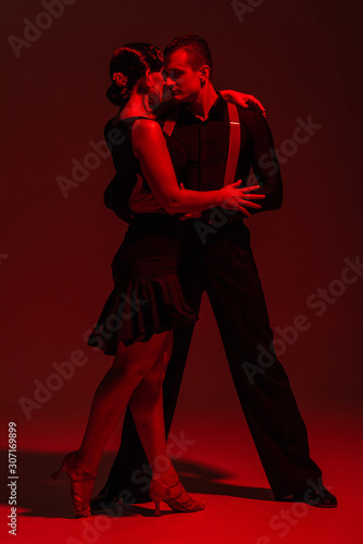 Canvas Print sensual couple of dancers performing tango on dark background with red illuminat