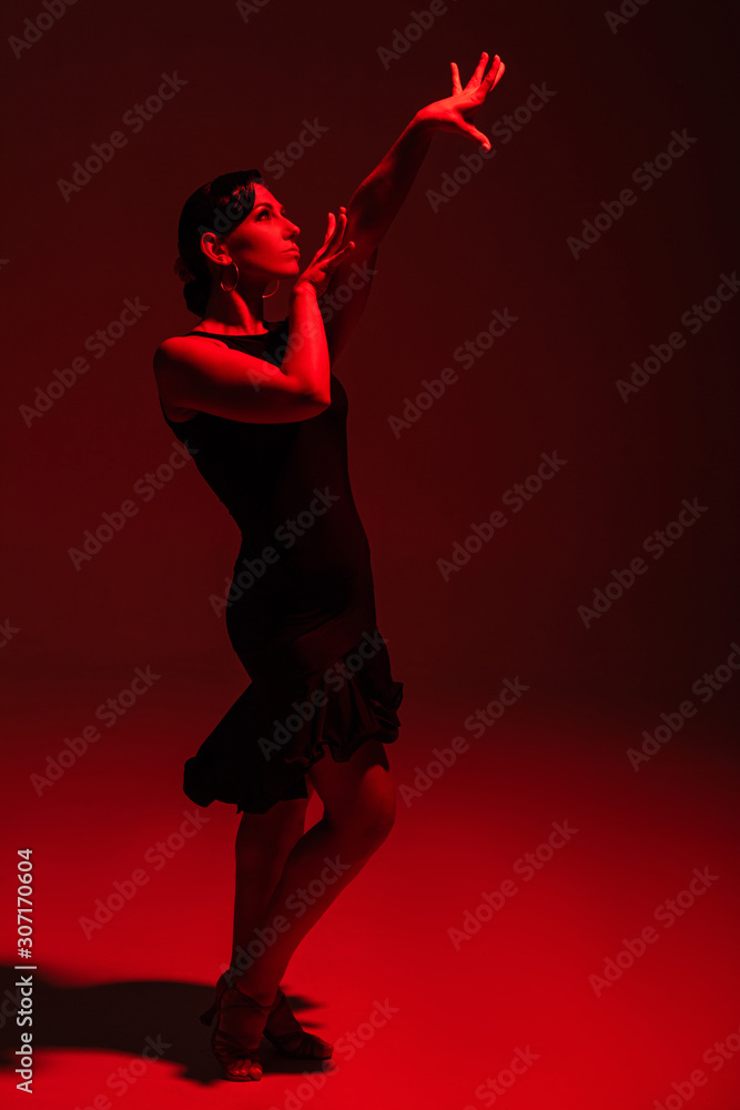 beautiful dancer in black dress performing tango on dark background with red illumination beautiful dancer in black dress performing tango on dark background with red illumination