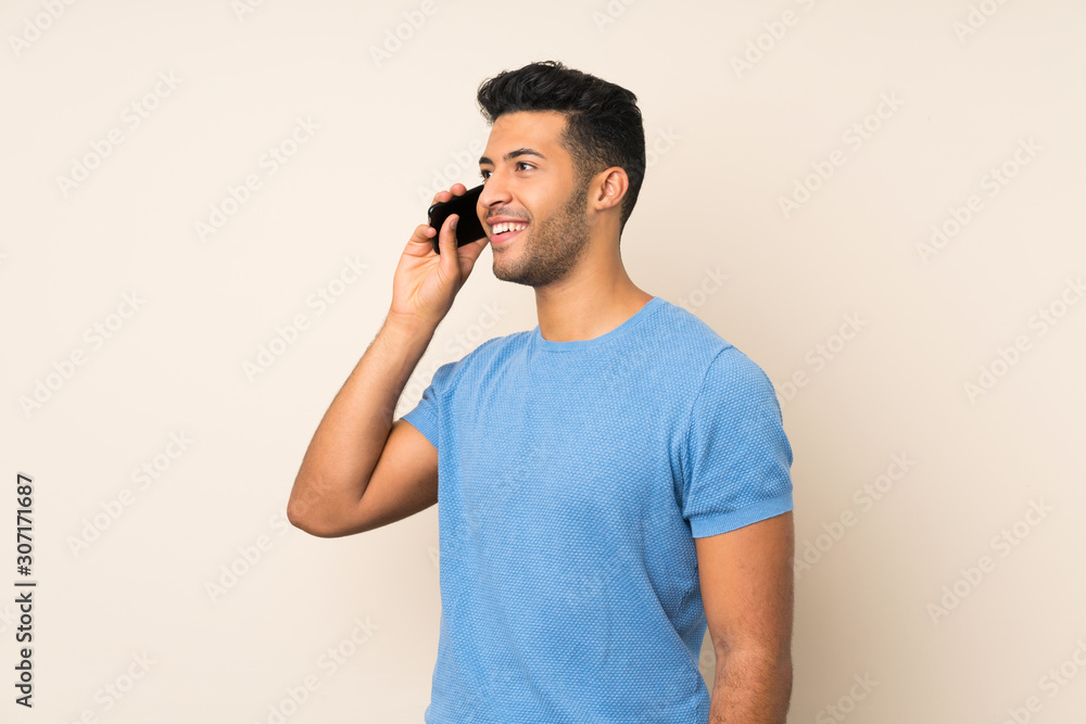 Young handsome man over isolated background keeping a conversation with the mobile phone Young handsome man over isolated background keeping a conversation with the mobile phone