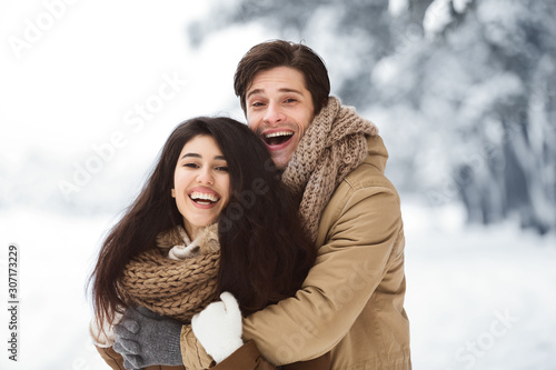 Cheerful Couple Of Lovers Embracing Standing In Winter Forest