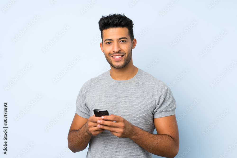 Young handsome man over isolated background sending a message or email with the mobile Young handsome man over isolated background sending a message or email with the mobile