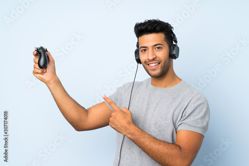 Young handsome man over isolated background playing at videogames