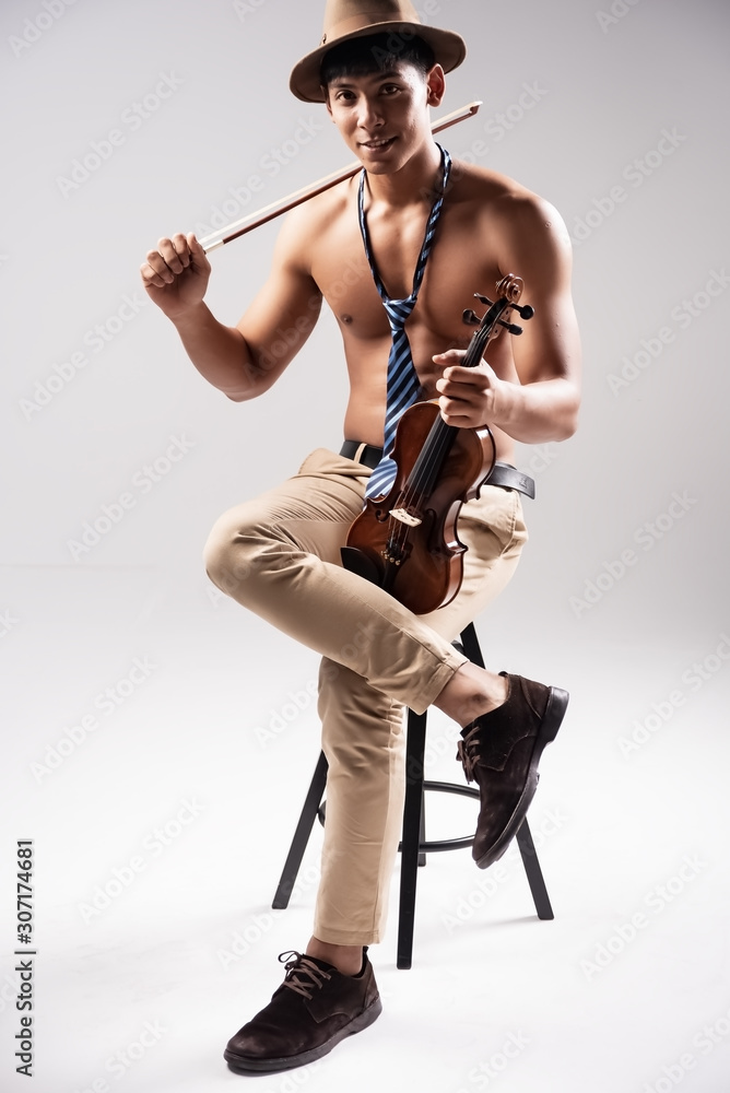 Th abstract art design background of handsome man sitting on wooden chait,hold violin and bow in hands,model posing ,with smart acting,blurry light around