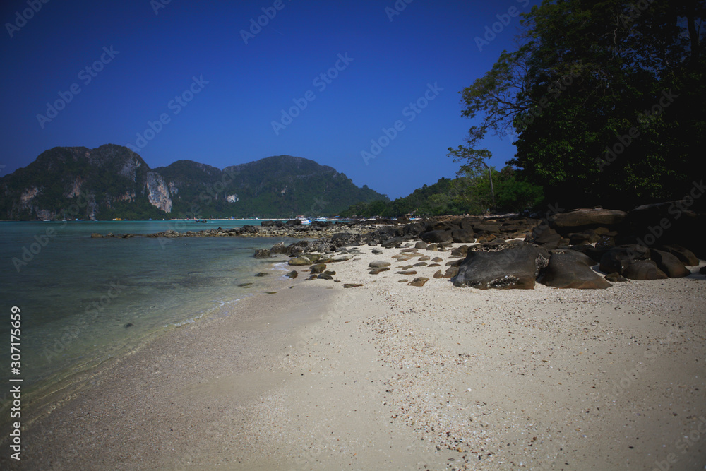 Stone beach, blue sea and mountains. Summer sunny day. Phi-Phi island Thailand.
