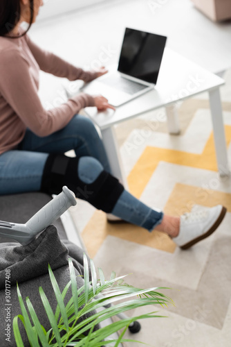 selective focus of woman with broken leg having online consultation with doctor on laptop at home