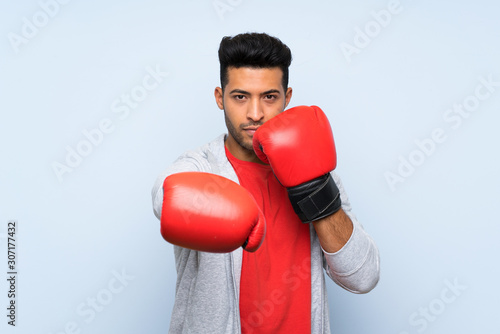 Sport man with boxing gloves over isolated blue wall © luismolinero