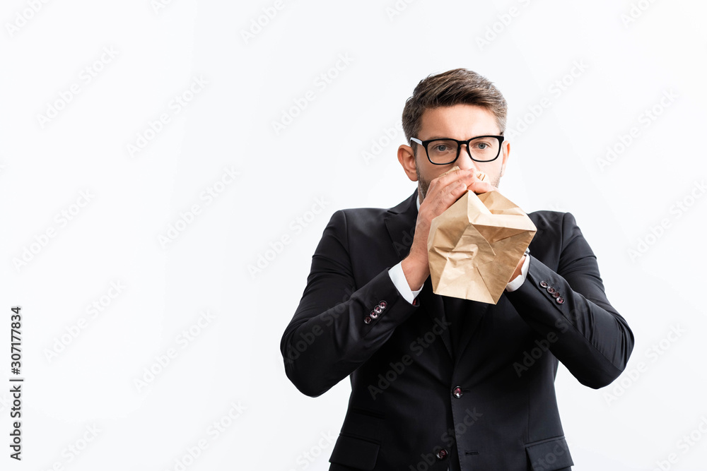 scared businessman in suit breathing in paper bag during conference isolated on white scared businessman in suit breathing in paper bag during conference isolated on white