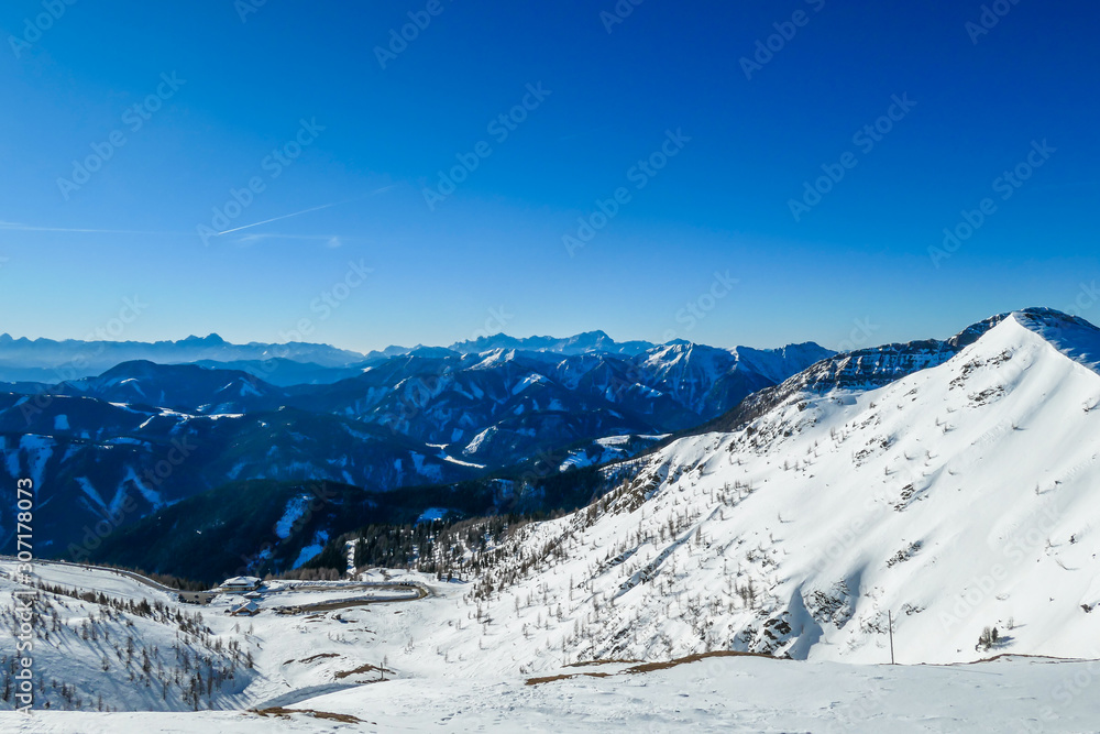 A panorama of a snow caped mountains Alps in Goldeck, Austria. Crispy and frosty morning. The ground is completely covered with snow. Endless mountain chains in the back. Serenity and solitude