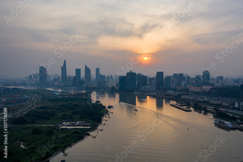 Saigon river sunset with extreme air pollution. Beautiful orange, red sky and reflections with Ho Chi Minh City, Vietnam Skyline. © Paul