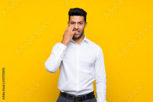 Young handsome man over isolated yellow background nervous and scared