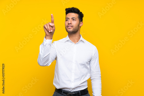 Slika na platnu Young handsome man over isolated yellow background touching on transparent scree