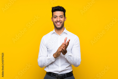 Young handsome man over isolated yellow background applauding