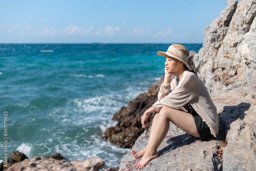 Woman sitting alone on seaside rock