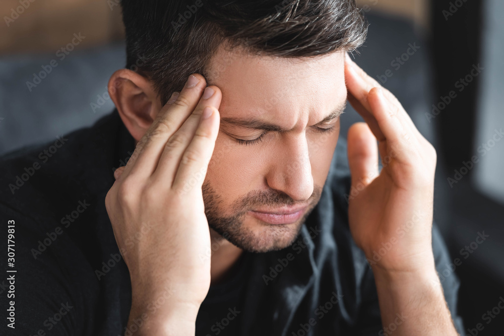 handsome man with headache touching head in apartment handsome man with headache touching head in apartment