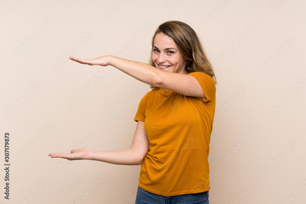 Young blonde girl over isolated background holding copyspace to insert an ad Young blonde girl over isolated background holding copyspace to insert an ad