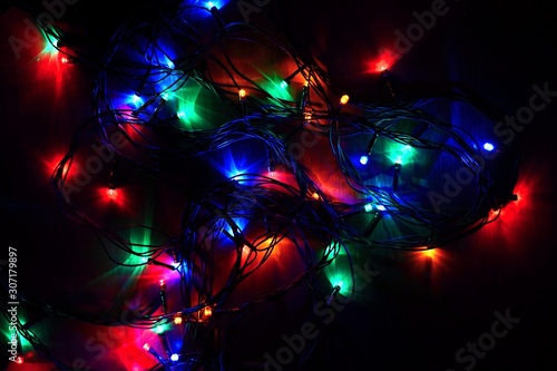 Christmas lights on black background with copy space. Colored reflecting surface.