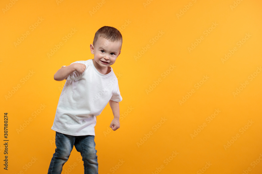 Kid boy wearing white t-shirt with space for your logo or design over yellow background