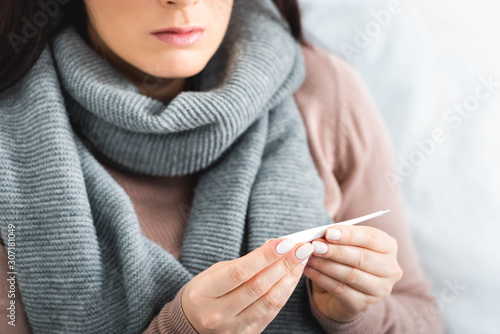 cropped view of ill woman with thermometer having fever at home